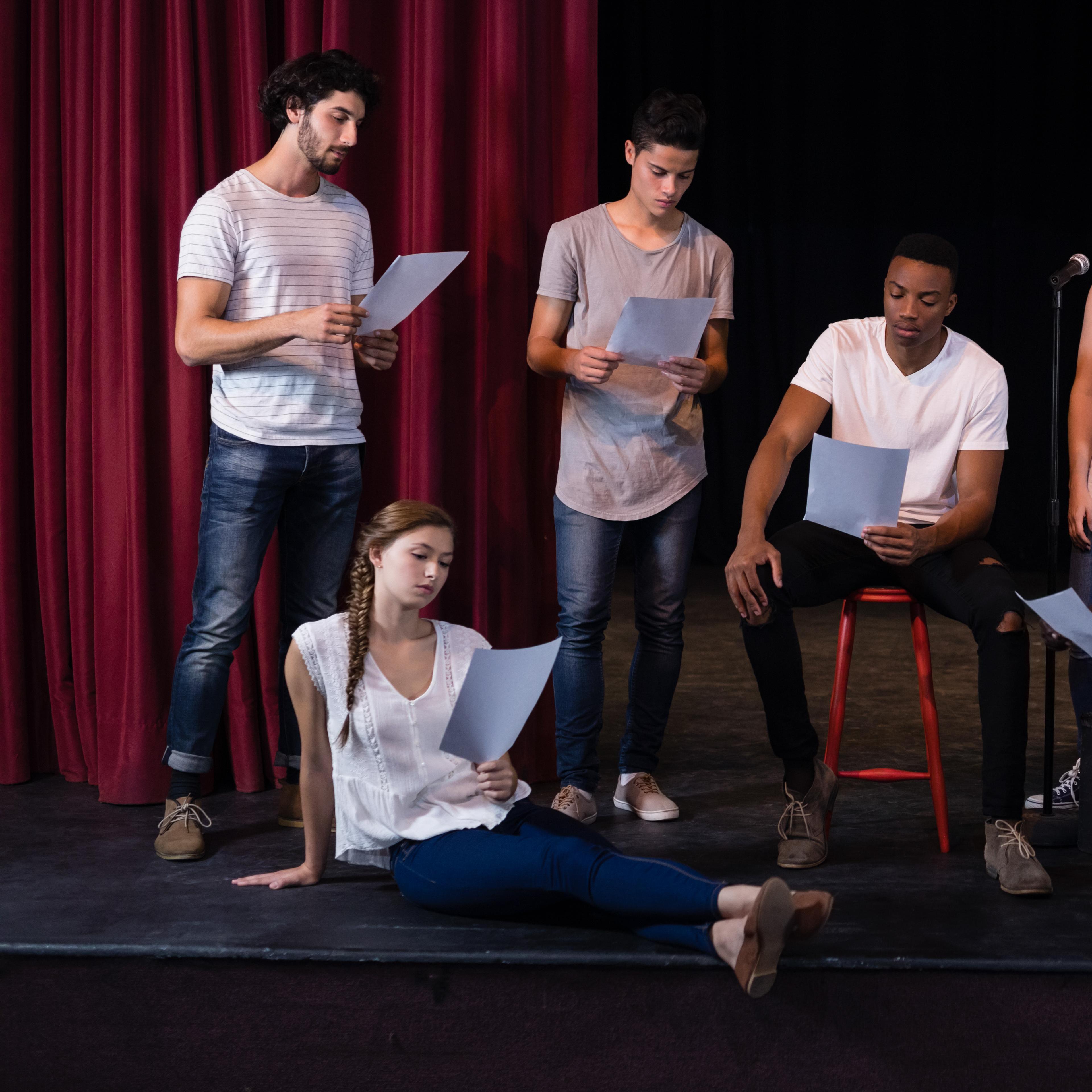 Theater actors reading their scripts on stage