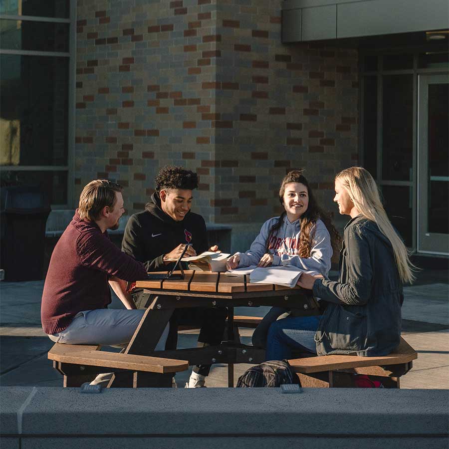 4 Nic Students sitting outside at a table