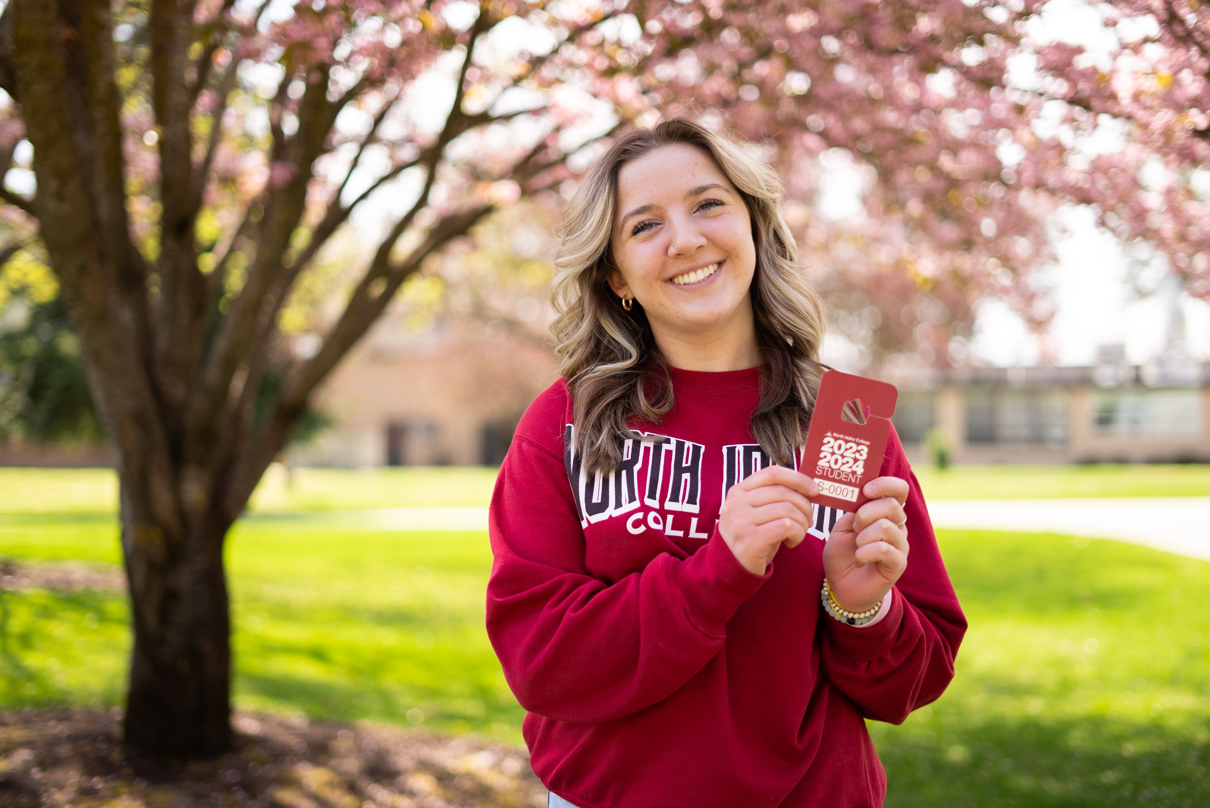 Female student holding a Parking Permit outside by a tree