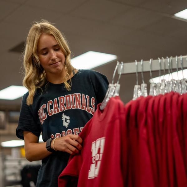 female student in the college bookstore looking at sweatshirts