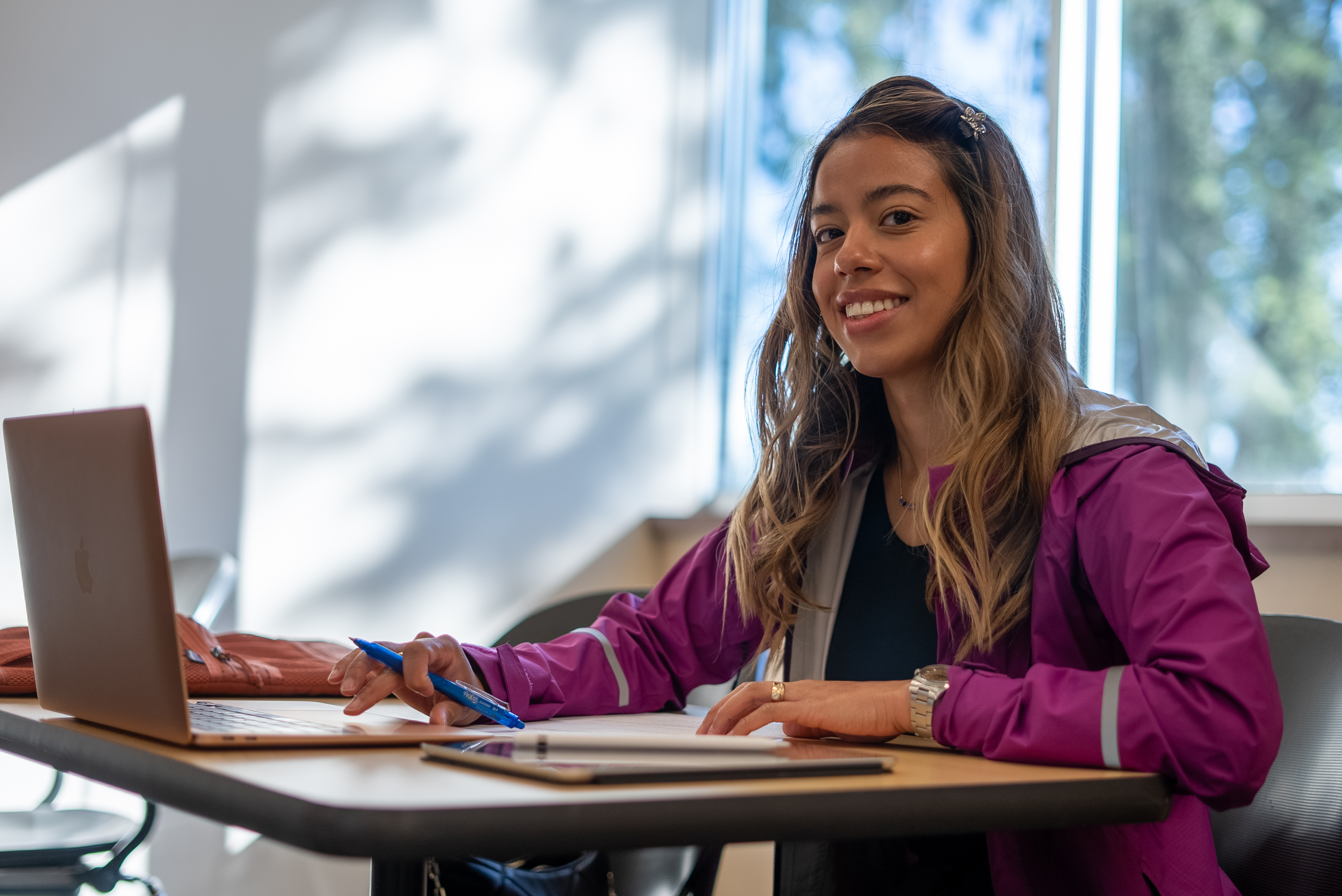 Female student smiling at table working on computer