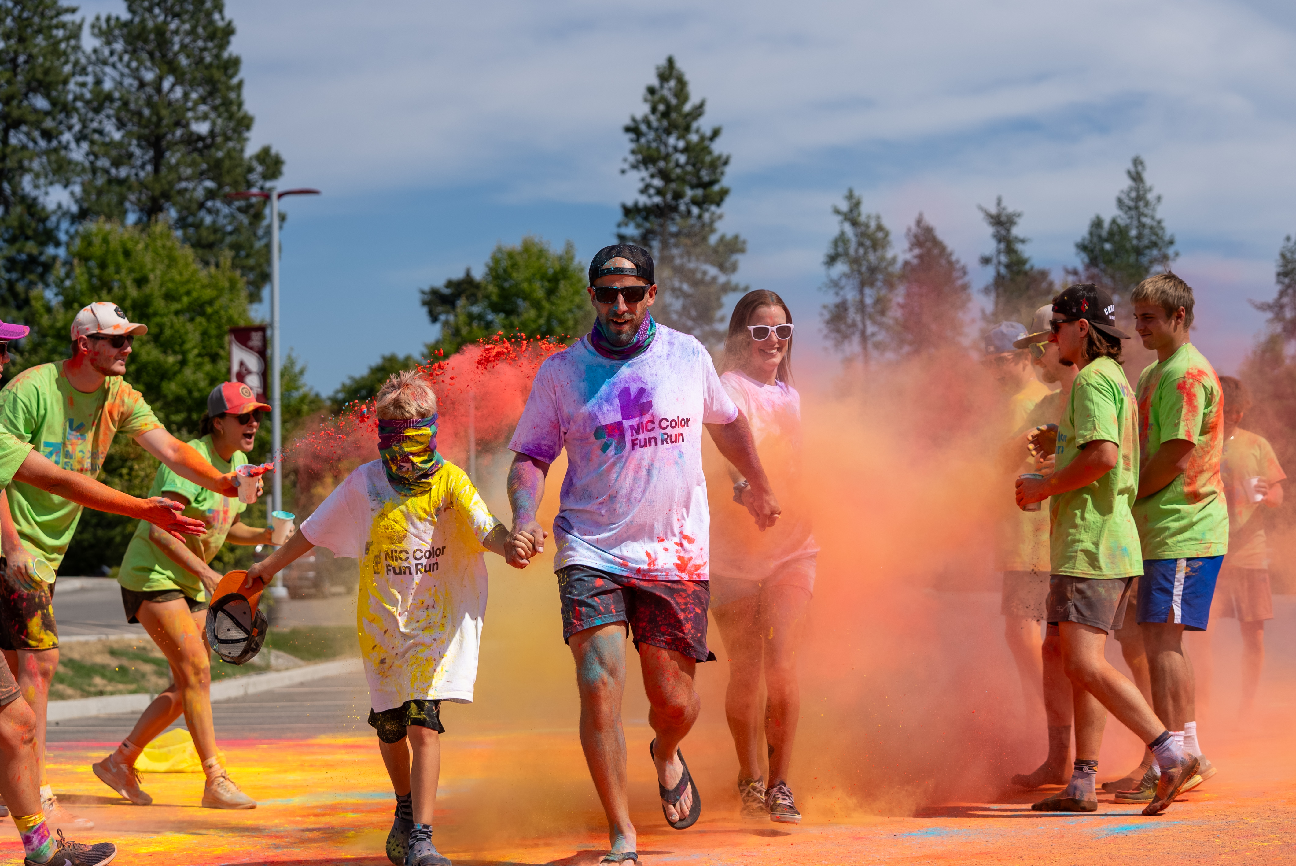 A group of participants run past volunteers throwing color powder at the inaugural NIC Color Fun Run on Aug. 23, 2025.